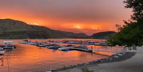 A serene lake at sunset, with boats docked and vibrant orange and pink hues reflecting on the water.