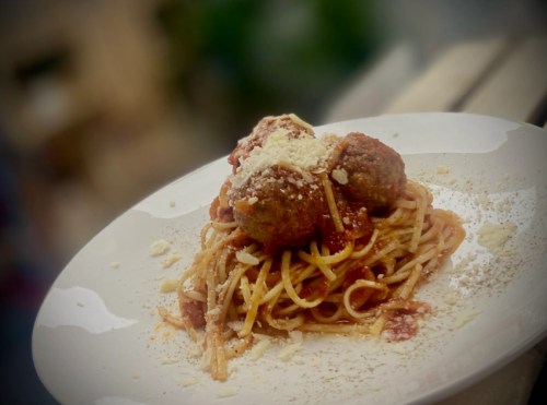 A plate of spaghetti topped with meatballs and grated cheese, served with a rich tomato sauce.