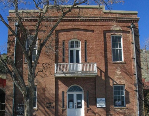 Historic brick building with large windows, a balcony, and a tree in front, labeled as a post office.