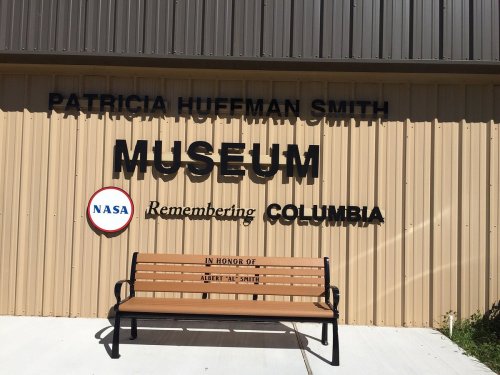 Sign for the Patricia Huffman Smith Museum, featuring NASA and a bench honoring Albert "Al" Smith.