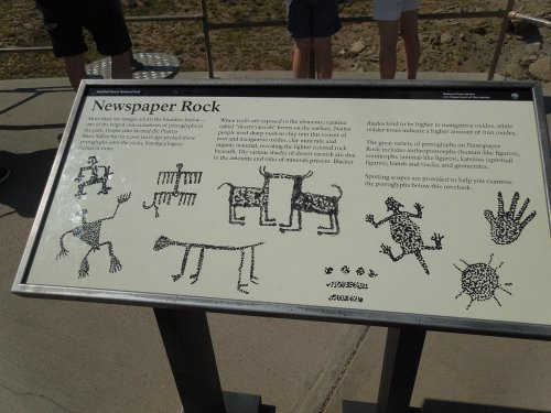 Sign displaying ancient petroglyphs on Newspaper Rock, featuring various animals and symbols etched into stone.