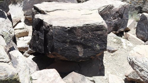A large, flat-topped rock surrounded by smaller stones in a rocky landscape.