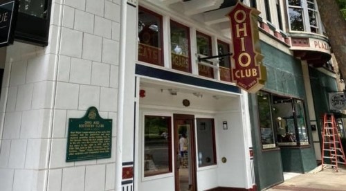 Exterior view of the Ohio Club, featuring a sign and historical marker, with a tree-lined street in the background.