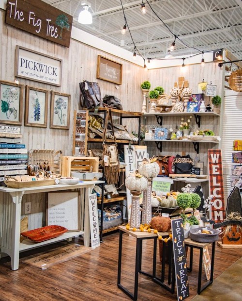 A cozy shop display featuring rustic decor, signs, and seasonal items, with wooden shelves and warm lighting.