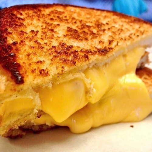 Close-up of a golden-brown grilled cheese sandwich with melted cheese oozing from the center.