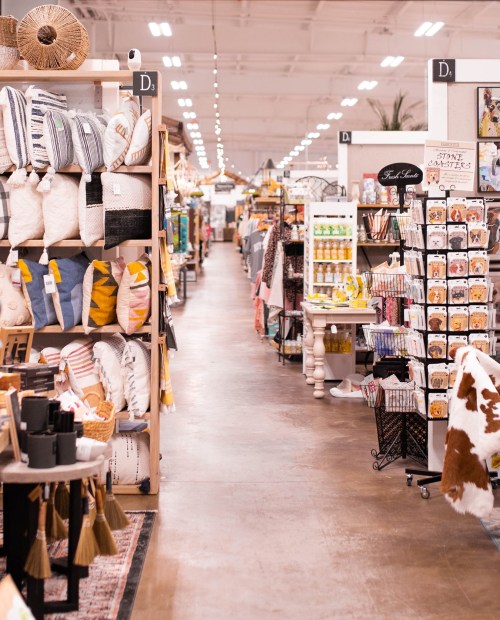 A spacious store aisle lined with home decor items, including pillows, kitchenware, and decorative accessories.