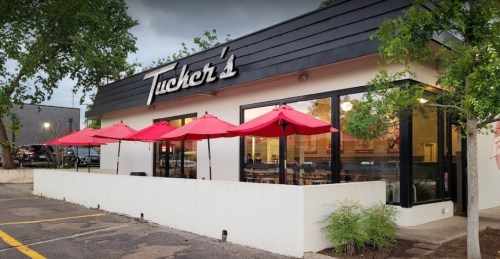 Exterior of Tucker's restaurant featuring red umbrellas on a patio and a modern design.