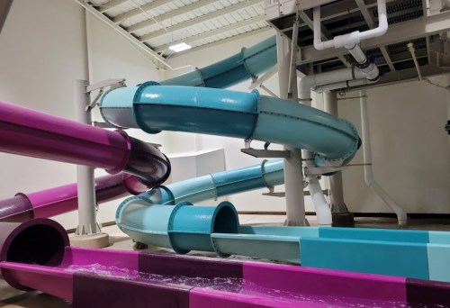 Colorful water slides twist and turn in an indoor water park setting.