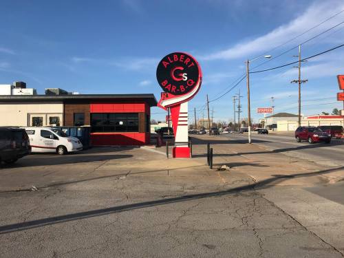 Sign for Albert's Bar-B-Q in front of a restaurant, with a clear blue sky and nearby streets visible.