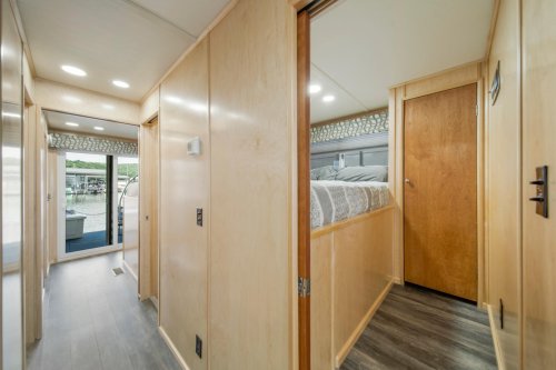 Interior view of a modern hallway leading to a bedroom, featuring wooden walls and a door at the end.