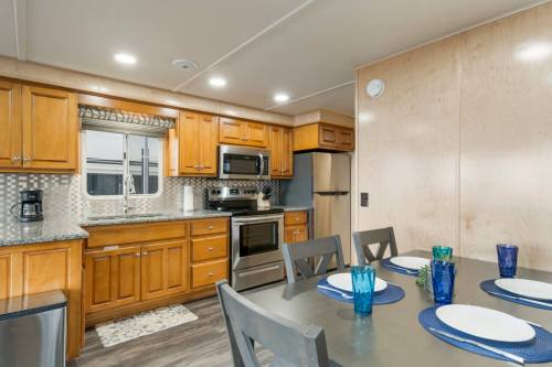 Modern kitchen with wooden cabinets, stainless steel appliances, and a dining table set with blue glasses and plates.