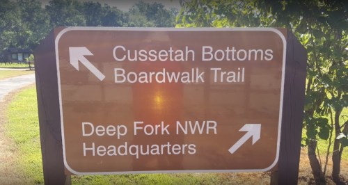 Signpost indicating directions to Cussetah Bottoms Boardwalk Trail and Deep Fork NWR Headquarters.