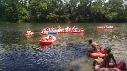 A group of people floating on colorful inner tubes in a river surrounded by lush greenery.