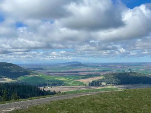 A panoramic view of rolling green hills and fields under a partly cloudy sky.