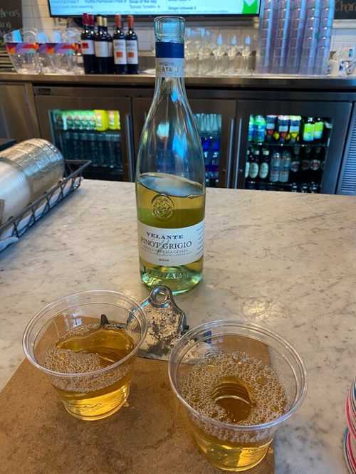 A bottle of Velante Pinot Grigio next to two cups of sparkling wine on a marble countertop.