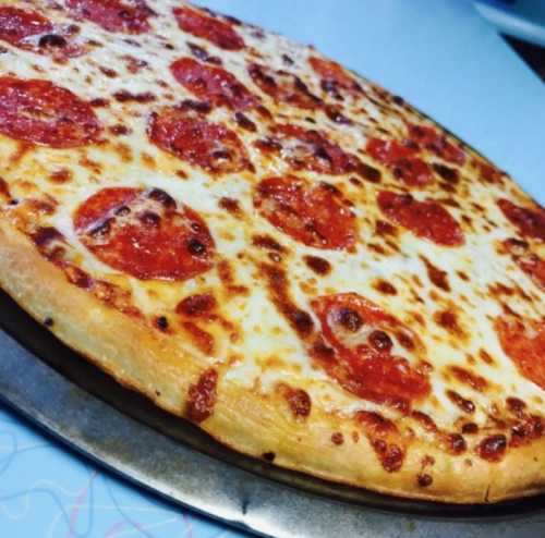 A freshly baked pepperoni pizza with melted cheese, sitting on a round metal tray.