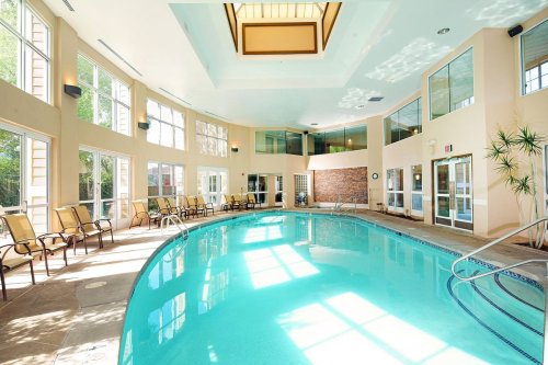Indoor swimming pool with large windows, lounge chairs, and natural light illuminating the space.