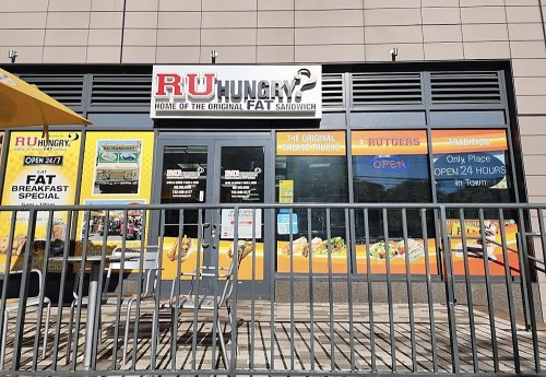 Exterior of RU Hungry? restaurant with signage promoting sandwiches and breakfast specials, featuring a bright yellow awning.