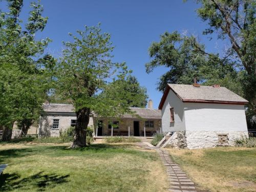 A historic building with a white exterior and a red roof, surrounded by green trees and a grassy area.