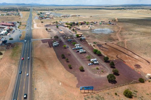 Aerial view of a rural area with a highway, scattered buildings, and a campsite surrounded by open land.