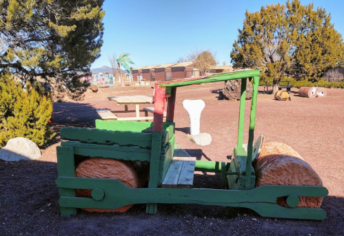 A colorful wooden roller toy in a park, surrounded by trees and a clear blue sky.