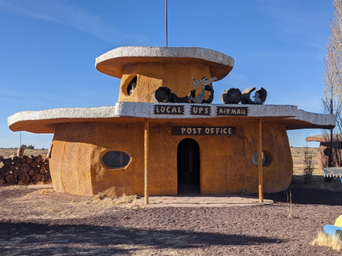 A unique, round building resembling a cartoonish post office with a sign reading "Local UPS Airmail."