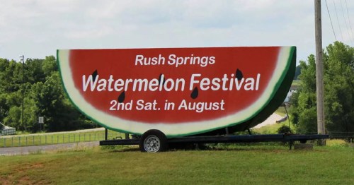 Sign for the Rush Springs Watermelon Festival, featuring a large watermelon slice, held the second Saturday in August.