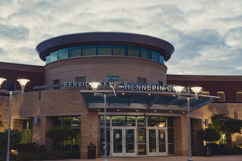 Exterior of the Hennepin County Service Center, featuring modern architecture and cloudy skies.
