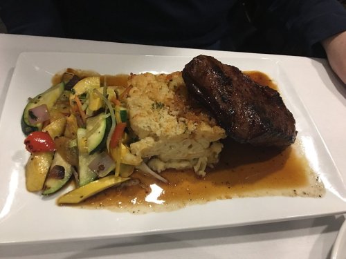 A plate featuring a grilled steak, creamy mashed potatoes, and sautéed mixed vegetables.