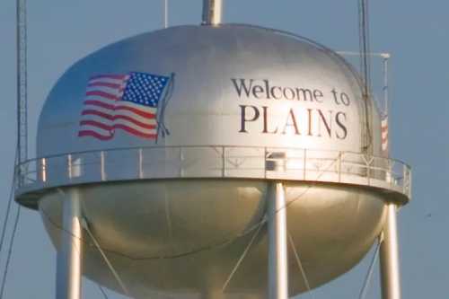 A water tower with "Welcome to Plains" and an American flag design.