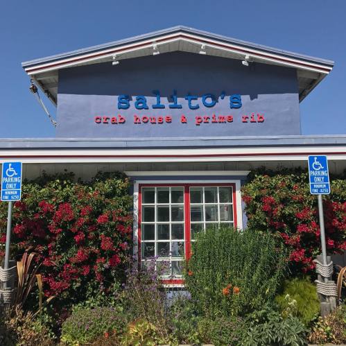 Exterior of Salito's Crab House & Prime Rib, featuring colorful flowers and blue sky, with accessible parking signs.