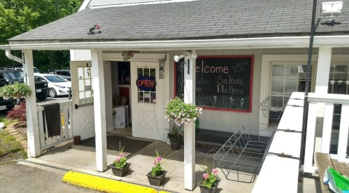 A welcoming restaurant entrance with a chalkboard menu, flower pots, and an "Open" sign.