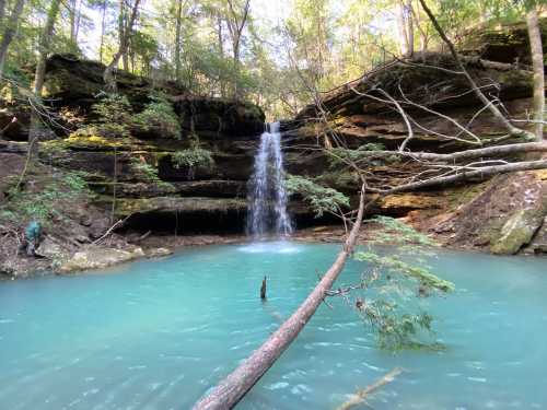 A serene waterfall cascades into a turquoise pool, surrounded by lush greenery and rocky cliffs.