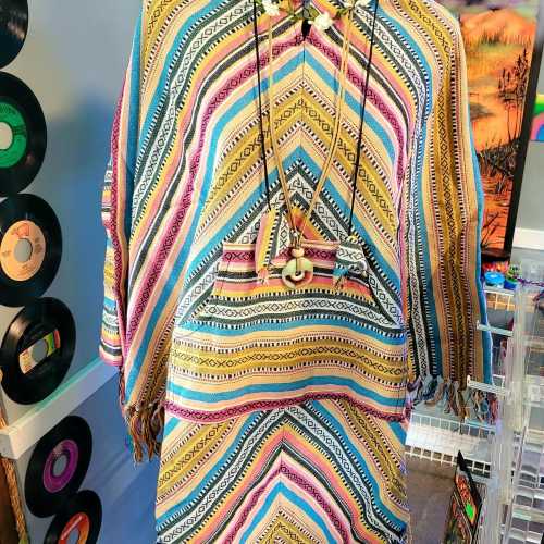 A colorful, patterned poncho hangs on display, surrounded by vintage records and vibrant decor.