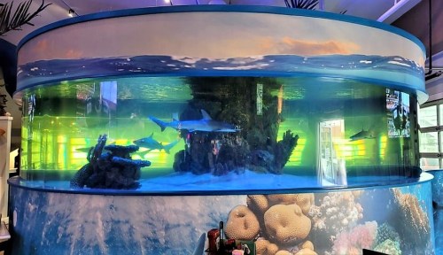 A large cylindrical aquarium with sharks and coral, surrounded by a colorful underwater scene.