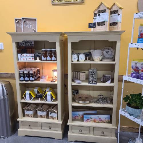 Two wooden display cabinets filled with jars, snacks, and decorative items, set against a light wall.