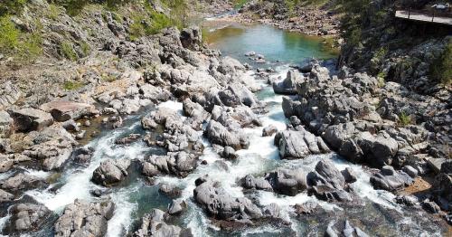 A scenic river flows through rocky terrain, surrounded by lush greenery and clear blue water.