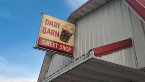 Sign for Dari Barn Sweet Shop featuring an ice cream cone, mounted on a building with a blue sky in the background.