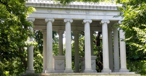 A classical stone structure with columns, surrounded by lush green trees, featuring the name "Palmer" on the front.