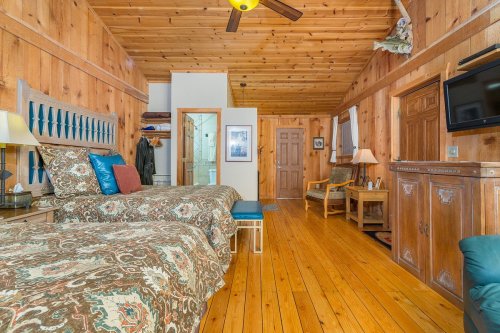 Cozy wooden room with two beds, a TV, and rustic decor, featuring warm lighting and a welcoming atmosphere.
