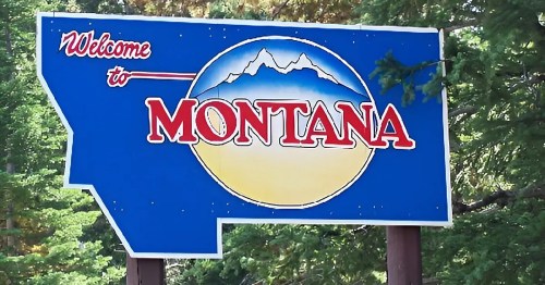 A colorful welcome sign for Montana featuring mountains and a sunset backdrop.