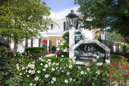 A charming bed and breakfast with a welcoming sign, surrounded by lush greenery and colorful flowers.