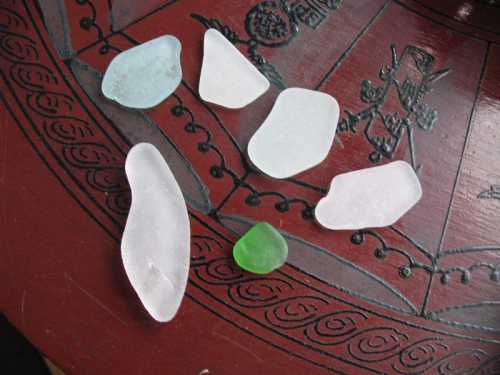 A collection of smooth, colorful sea glass pieces on a decorative wooden surface.