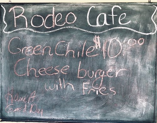 Chalkboard menu at Rodeo Cafe featuring a Green Chile cheeseburger with fries for $10.00.