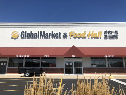 Exterior of Global Market & Food Hall, featuring a food court, café, and grocery, with a clear blue sky above.