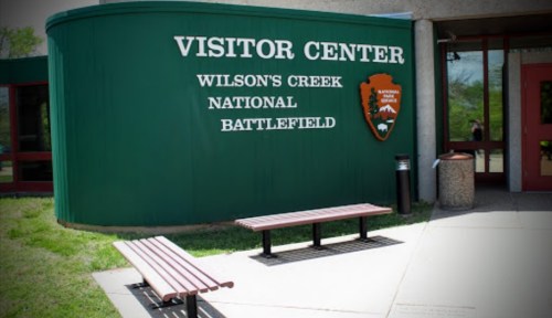Exterior of the Visitor Center at Wilson's Creek National Battlefield, featuring benches and a green facade.