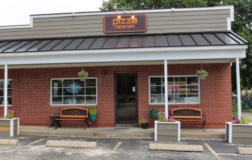 Exterior of a pizza restaurant named "Pizza Heaven," featuring a brick facade, planters, and a welcoming entrance.