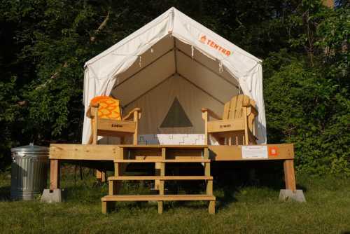 A glamping tent on a wooden platform with two chairs and steps, surrounded by greenery.