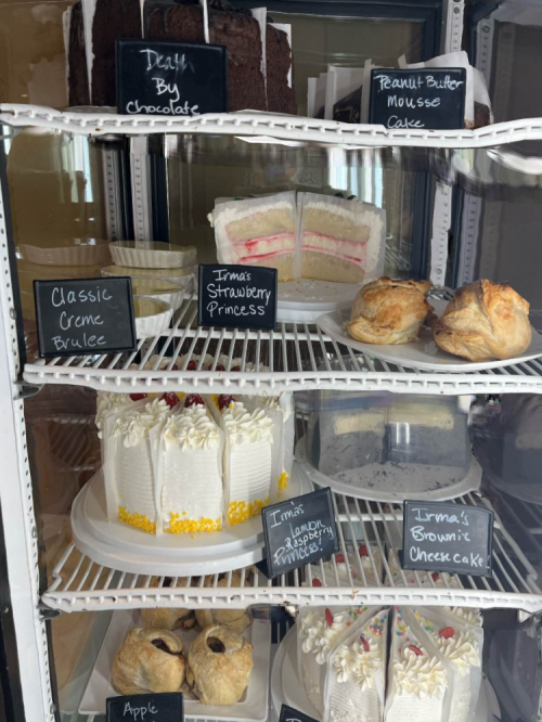 A display case filled with various cakes and pastries, including chocolate cake, mousse cake, and fruit tarts.