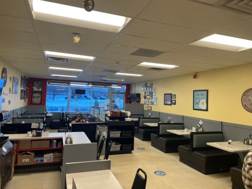 A cozy diner interior with booths, tables, and a large window showing a snowy view outside.